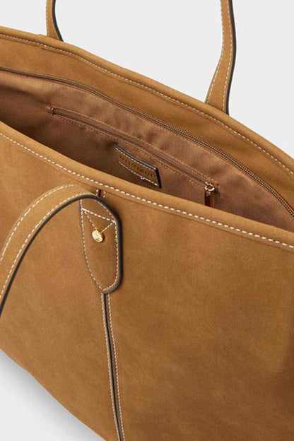 Tan tote bag close-up with front zip pocket and small metal logo badge