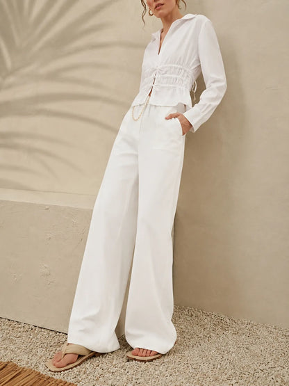 Licci white long-sleeve jumpsuit with smocked peplum waist and wide-leg pants