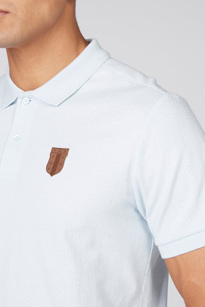 Light blue polo shirt close-up with button collar and chest logo patch