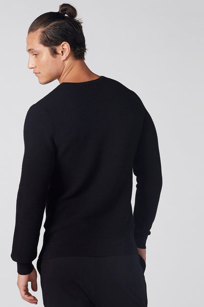 Black long-sleeve knit top from back view with ribbed cuffs
