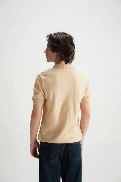 Beige polo shirt back view with short sleeves and clean yoke seam.