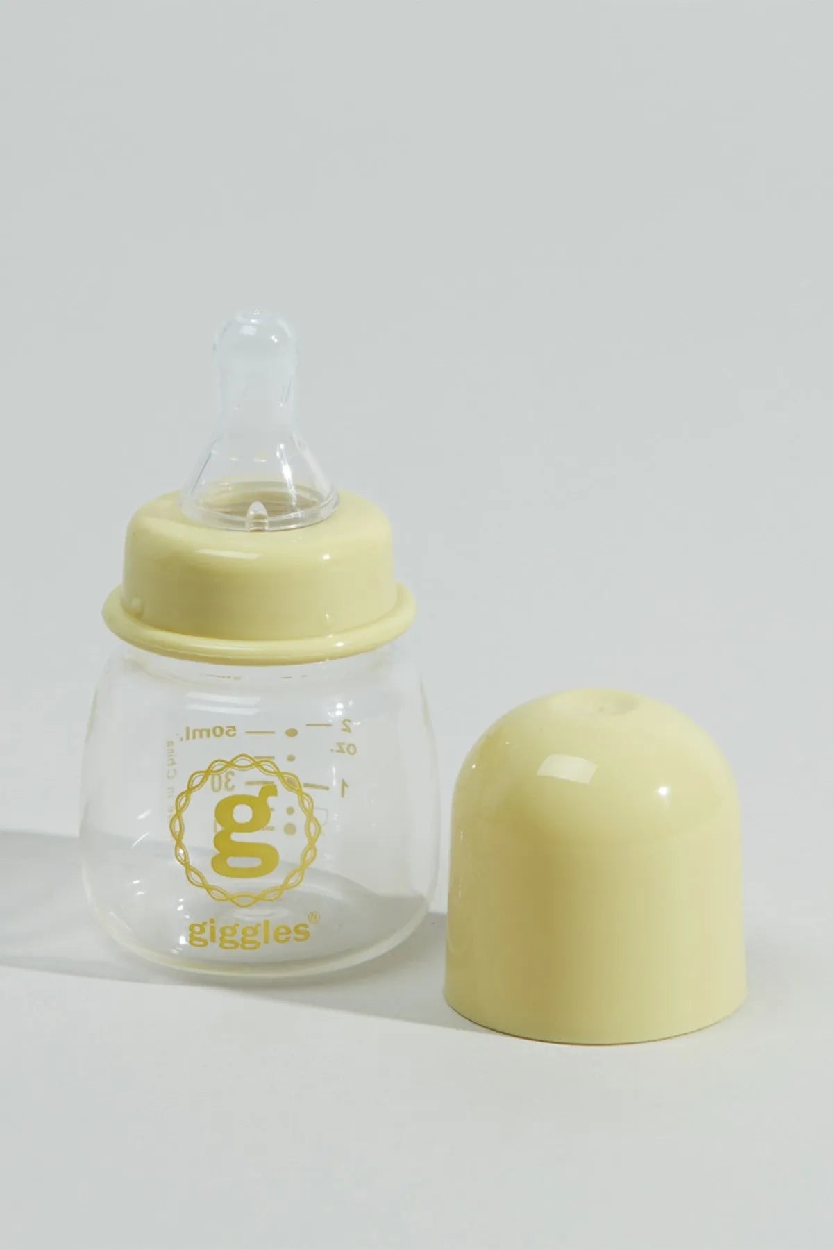 Yellow capped baby bottle with clear body and printed 'giggles' logo