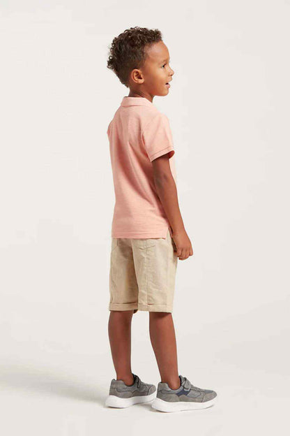 Kids pink polo shirt with beige shorts, side view