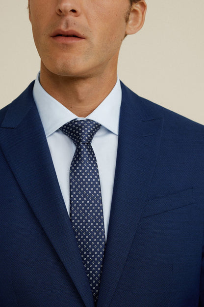 Men's navy blue suit jacket close-up with light shirt collar and patterned tie
