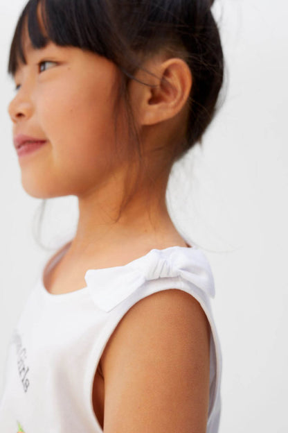 Off-white girls' sleeveless tank top with ruffled shoulder detail, side view