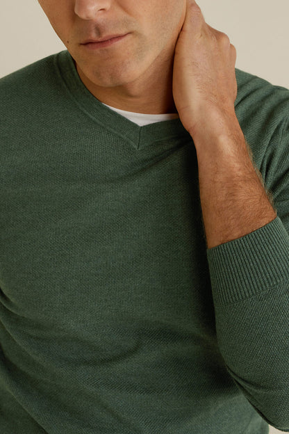 Green knit V-neck sweater close-up with ribbed collar and sleeve cuff
