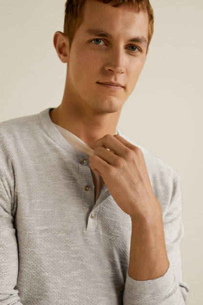 Beige long-sleeve henley shirt with three-button henley collar, close-up