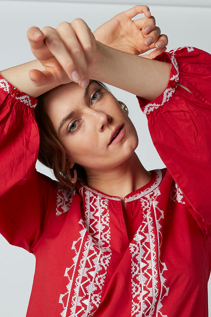 Close-up of red embroidered neckline and cuffs on long-sleeve tunic dress