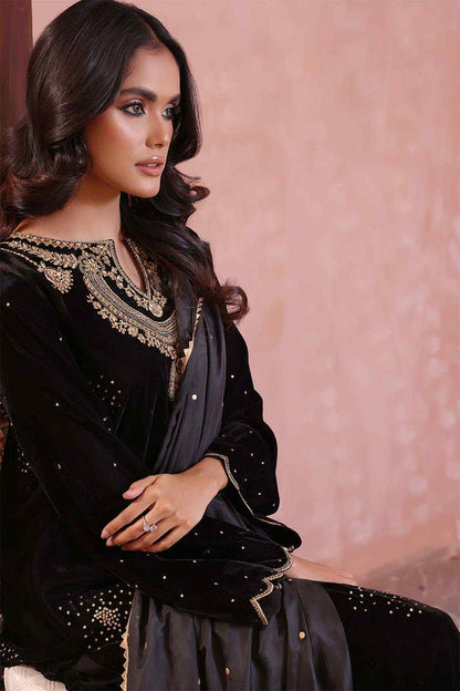 Close-up of black embellished dress neckline and cuffs with gold trim and beads