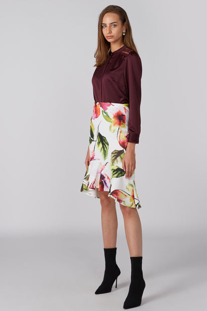 Burgundy blouse with ruffled neckline and floral skirt, full-length standing view