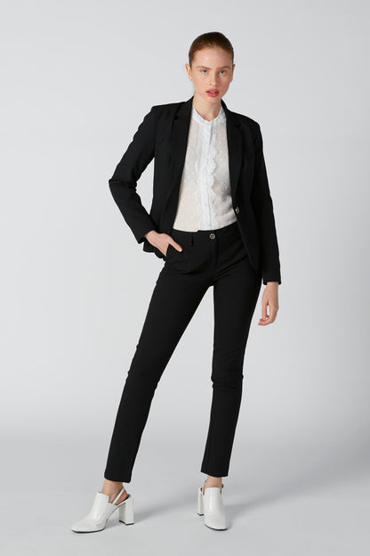 Black blazer layered over white dotted zip-front top with stand collar