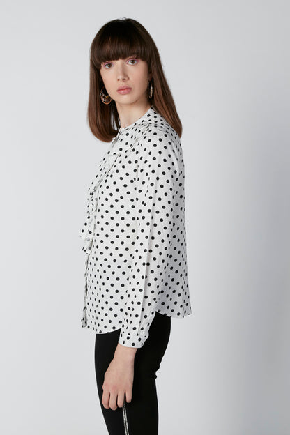 White polka-dot button-front blouse with long sleeves and curved neckline