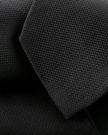 Black textured necktie close-up with woven grid pattern