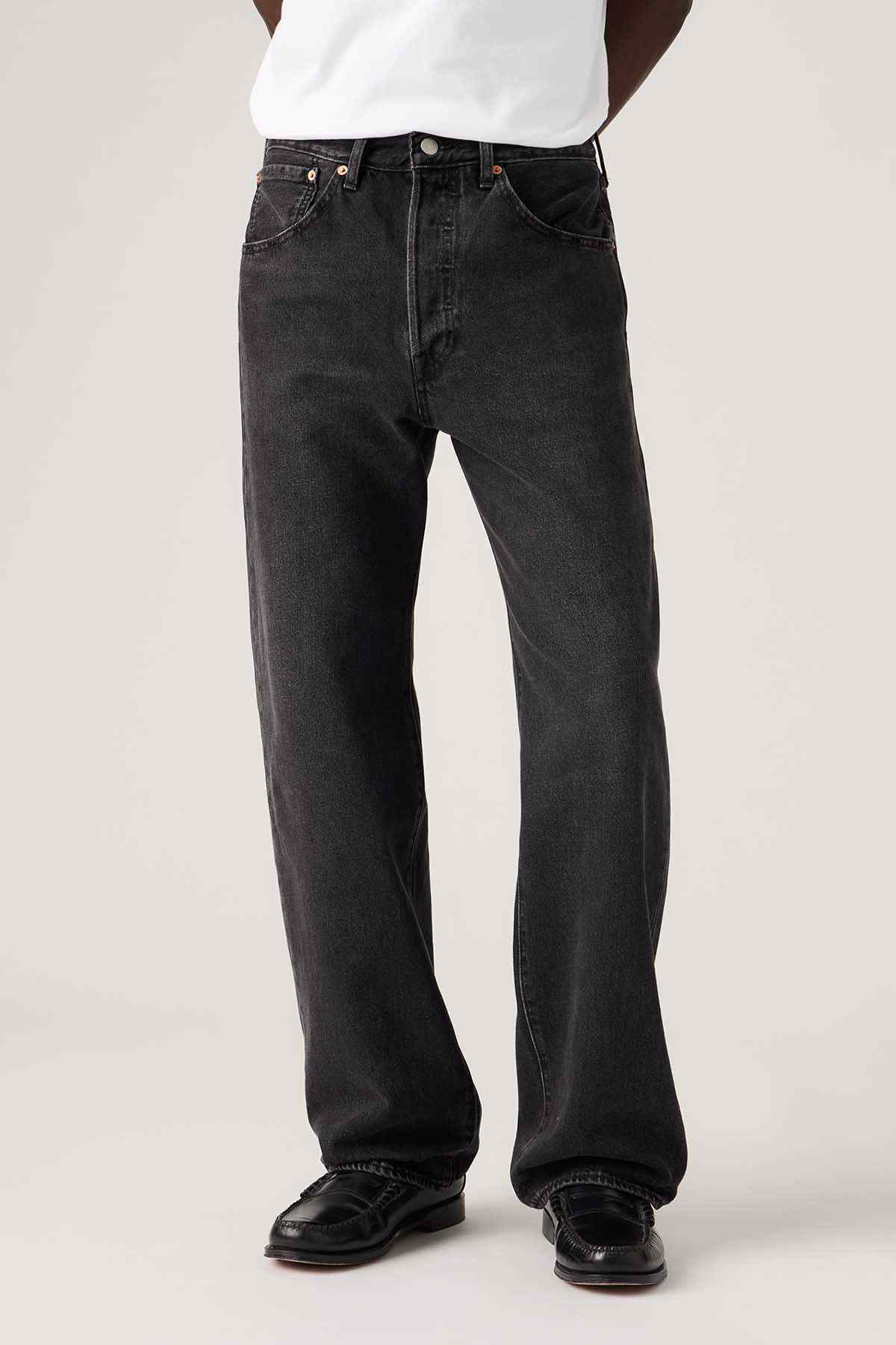 Black denim jeans close-up: button fly, straight legs, stitched seams