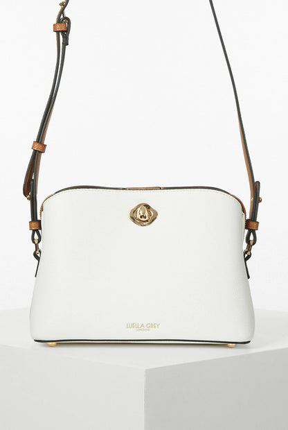 White crossbody handbag with gold logo clasp and tan leather strap