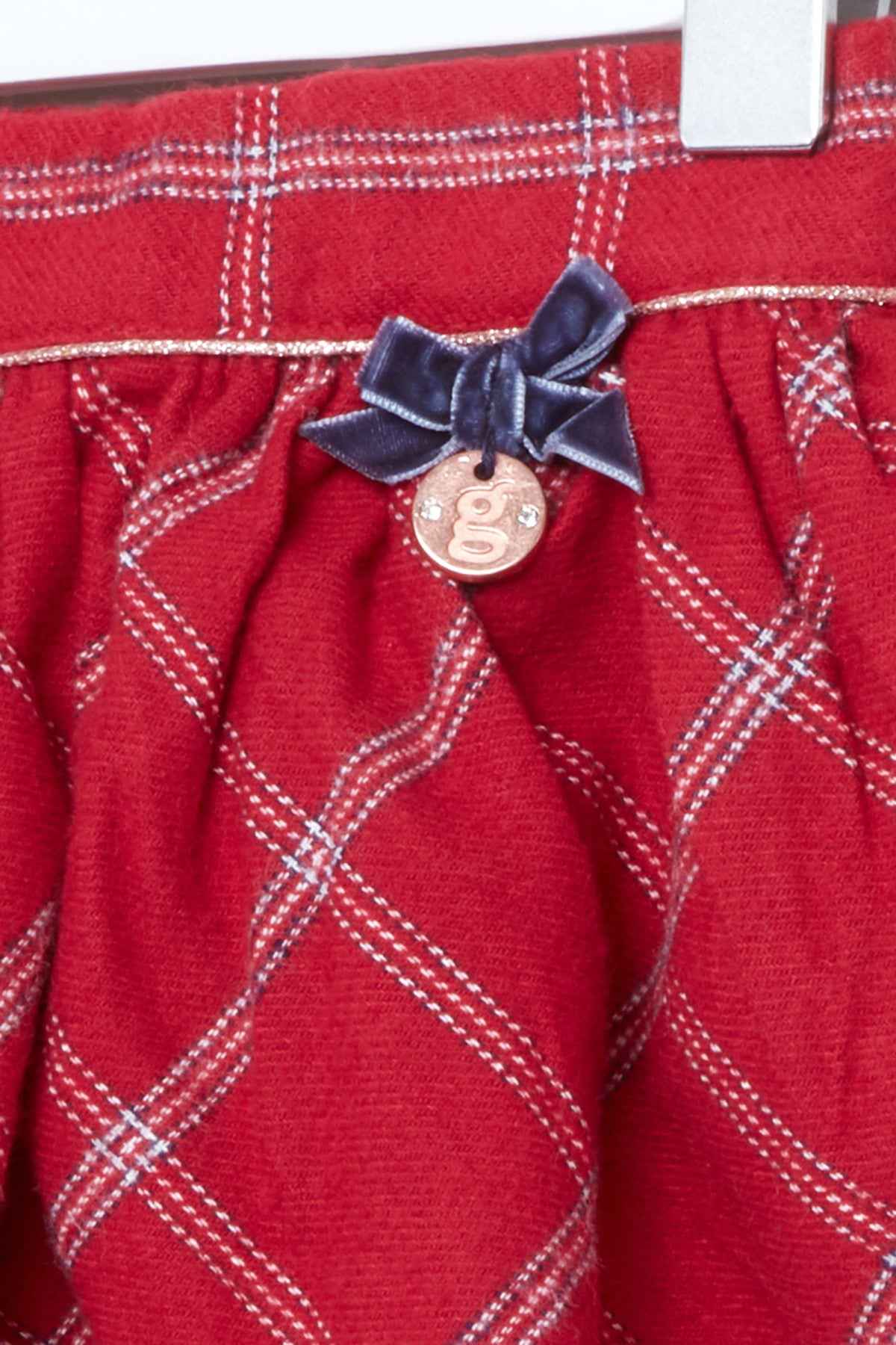 Red plaid skirt detail with navy bow and round button charm