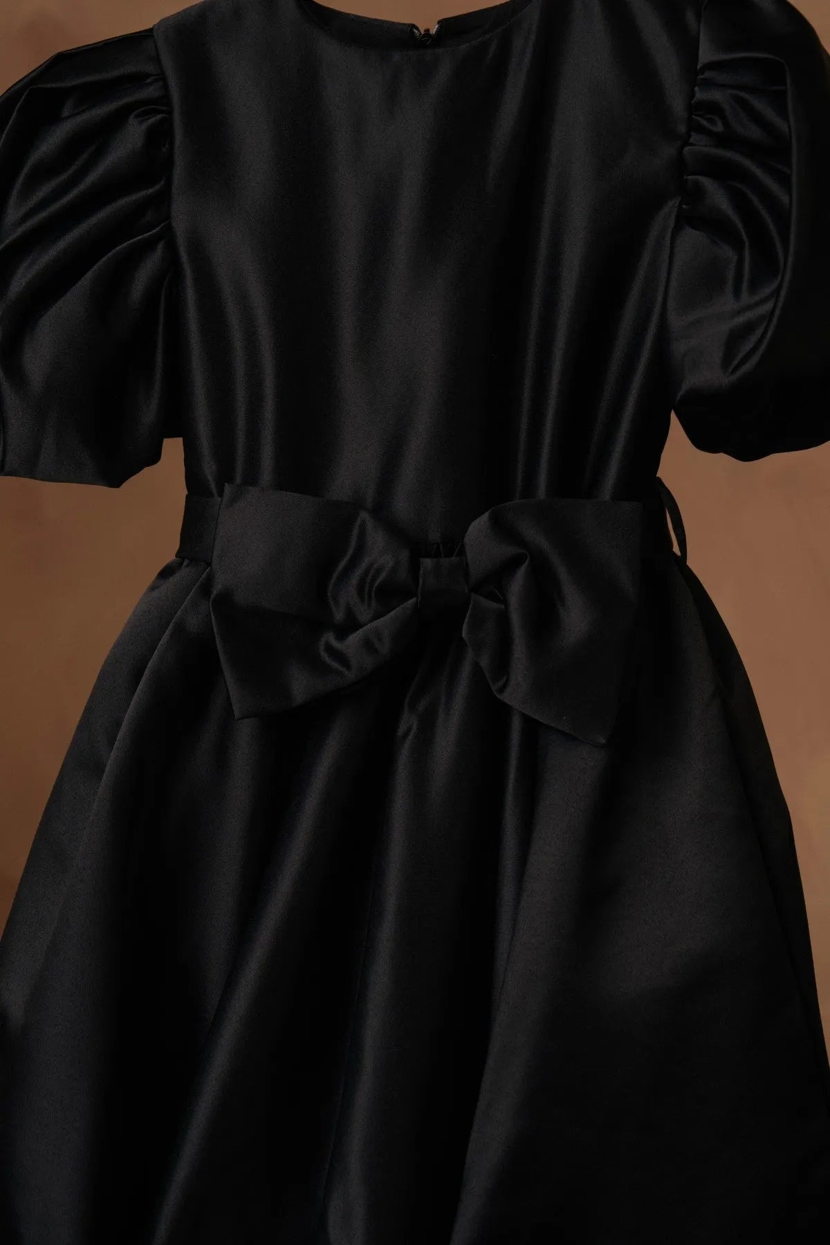 Black puff-sleeve satin dress with gathered neckline and tied bow waist