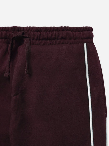 Burgundy cotton track pants close-up: elastic waistband and drawstring, white side stripe