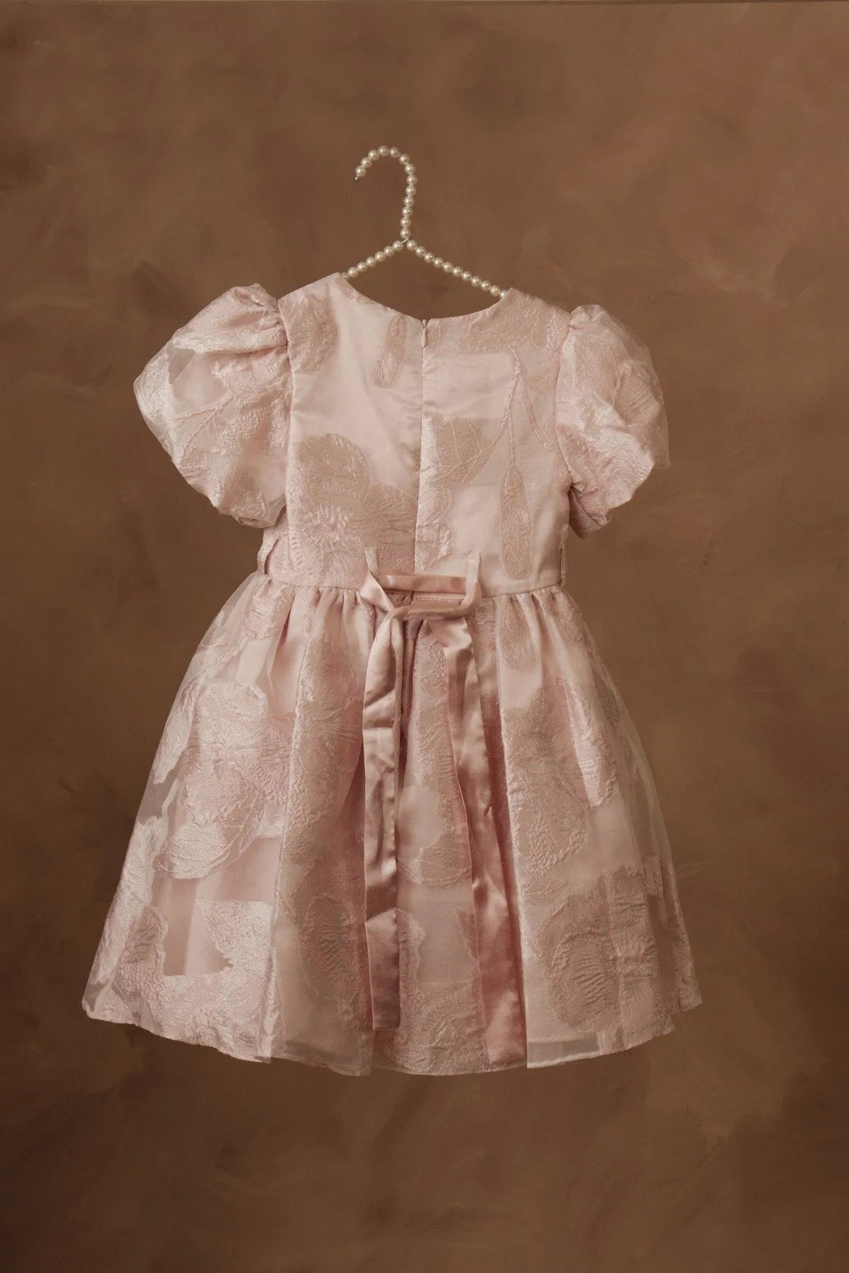 Light pink girls skater dress with puff sleeves, belted waist, and pleated skirt