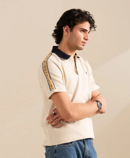 Fitted off-white polo shirt with navy collar and button placket; logo and sleeve stripe.