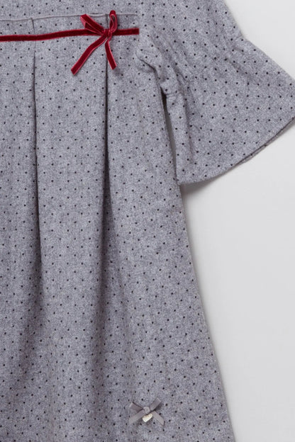 Baby dress detail, light gray dotted fabric with red bow trim and pleated skirt