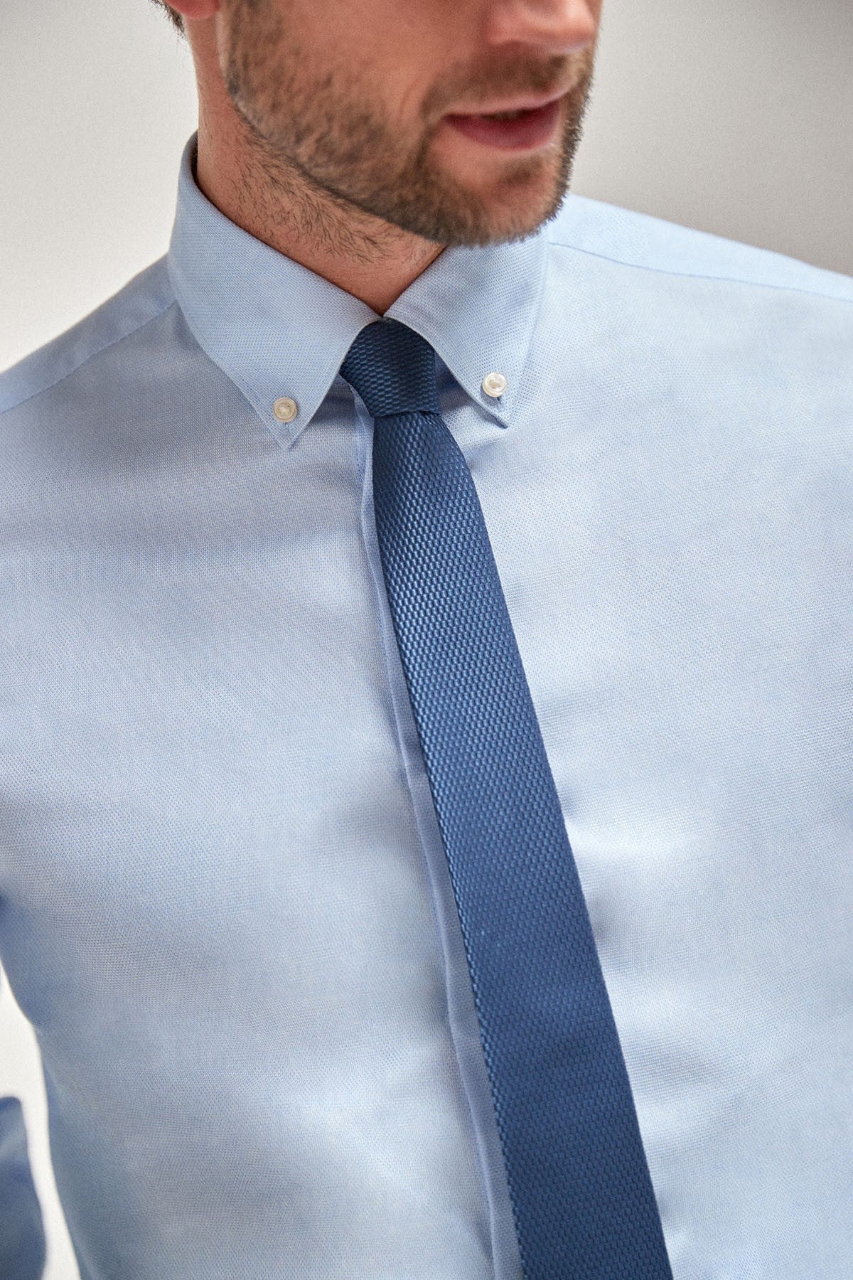 Light blue dress shirt with textured navy tie and collar buttons