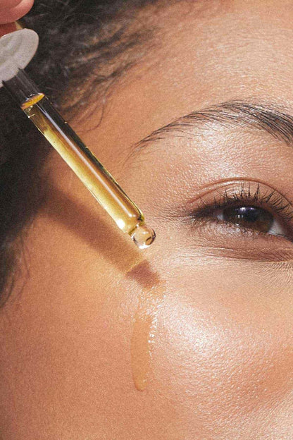 Kora Organics Noni Glow face oil dropper applying oil near the eye