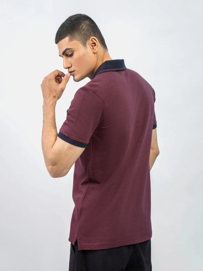 Maroon short-sleeve polo shirt with navy collar and two-button front, side view