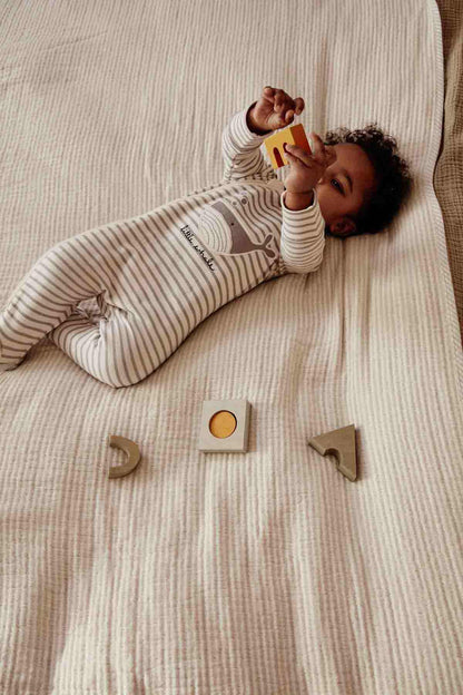 Striped footed romper with snap buttons, long sleeves, worn while lying.