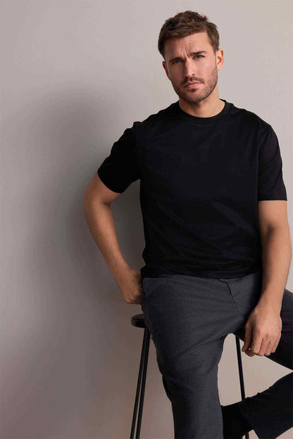 Next black crew-neck short-sleeve T-shirt on model, seated pose