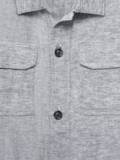 Grey button-up shirt detail with two chest pockets and dark front buttons