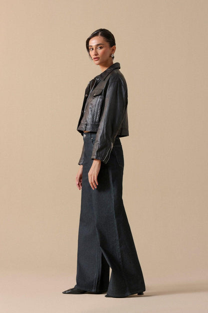 Women’s blue-black wide-leg jeans with black leather jacket, side profile