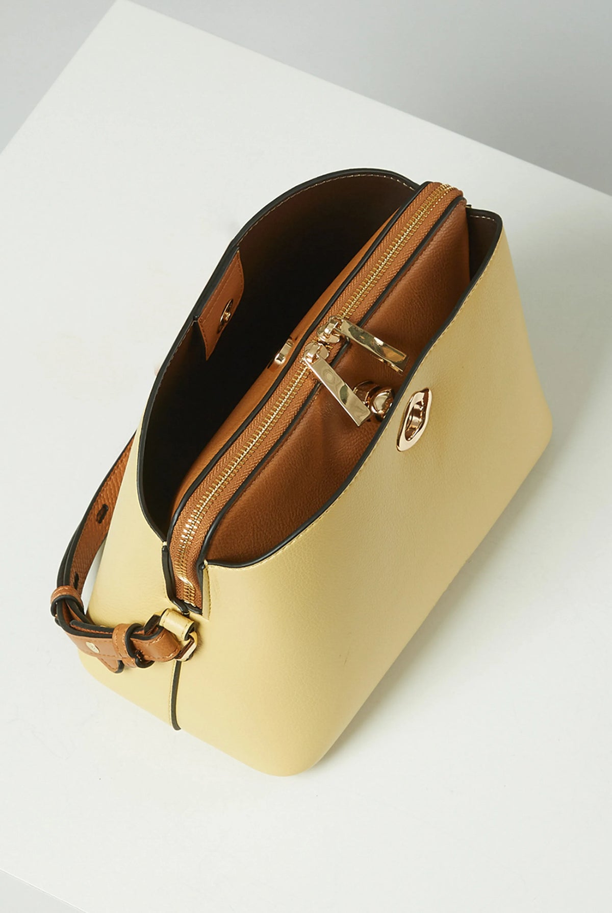 Yellow handbag with brown leather strap and gold hardware, angled side view