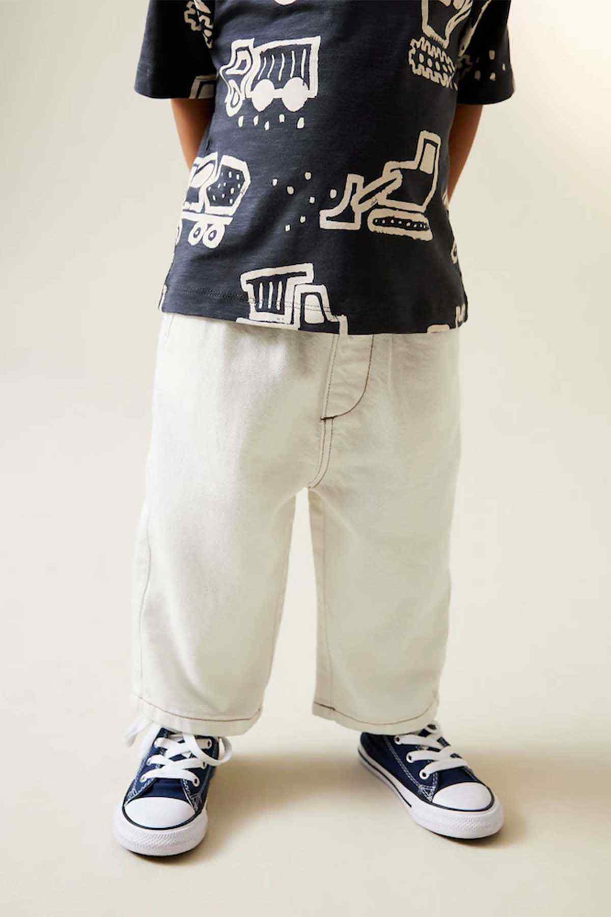 Kids black graphic T-shirt with ecru pants, close view of legs and sneakers