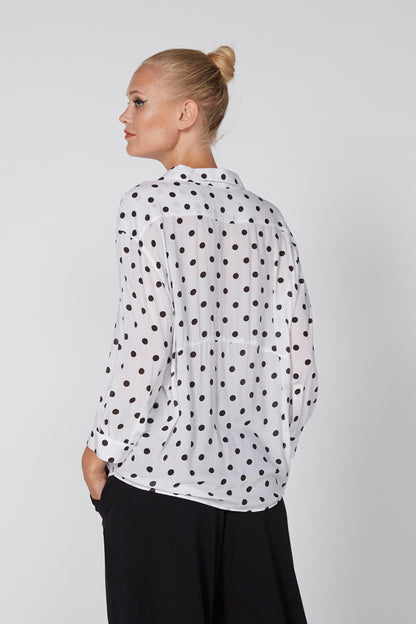 White polka-dot button-up shirt with collar, three-quarter back view