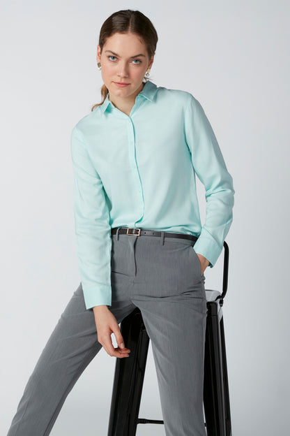 Light turquoise collared button-up shirt with long sleeves; tucked into gray trousers