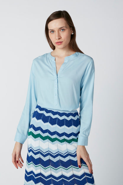 Light blue button-front blouse with split neckline, over chevron zigzag striped skirt