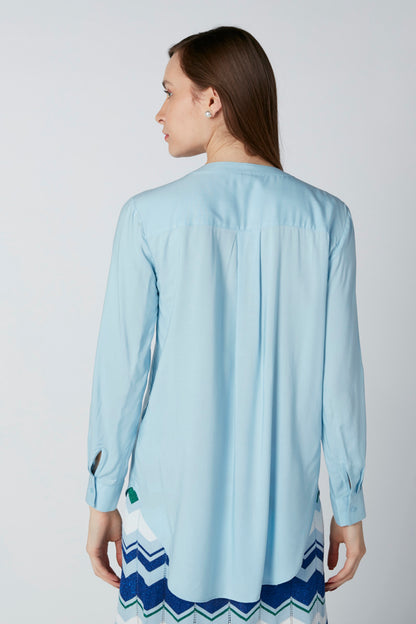 Light blue back-tucked blouse, 3/4 sleeves, with chevron striped skirt hem