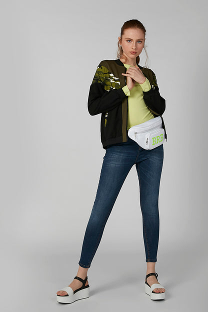 Black long-sleeve jacket with green graphic, worn with blue jeans and crossbody bag