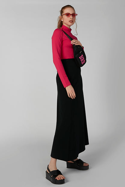 Pink high-neck long-sleeve top with black skirt, side view on model.