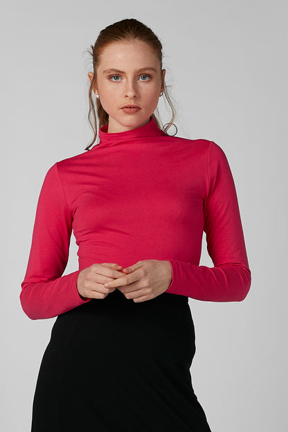 Pink high-neck long-sleeve top with black skirt, front close-up.
