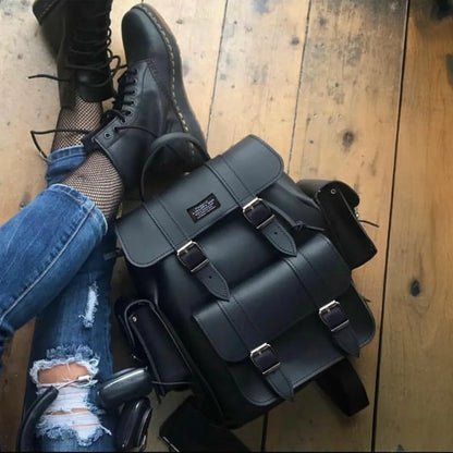 Black leather-look backpack with flap, multiple buckles, and front pocket