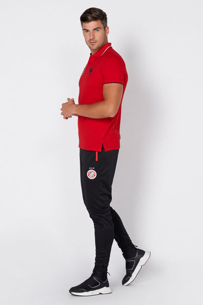 Red polo shirt and black track pants with circular logo patch