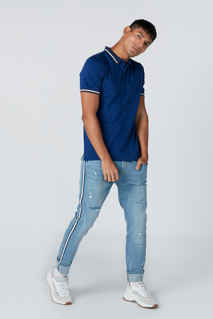 Blue polo shirt with white-trim collar and short sleeves, worn with light blue jeans.