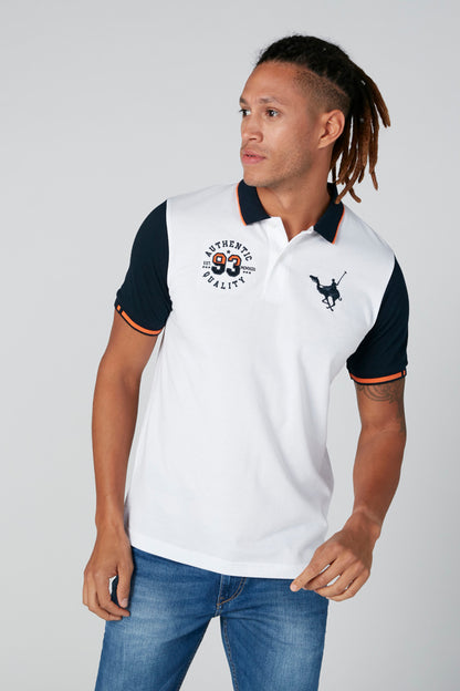 White polo shirt with navy collar, front crest and bull graphic