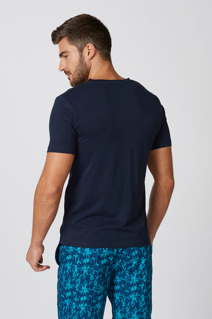Men's navy short-sleeve henley shirt with blue tropical print shorts, back view