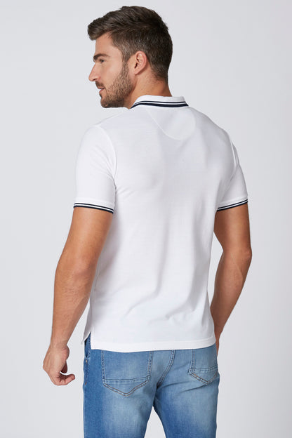 White polo shirt with navy-trim collar and sleeve edging, back view over jeans