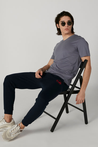 Navy jogger pants with ankle cuffs and small red logo on thigh