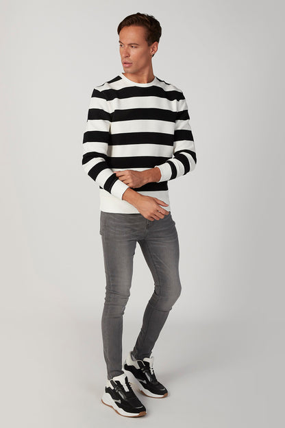 Men's striped crewneck sweater with black-and-white bands, worn with jeans