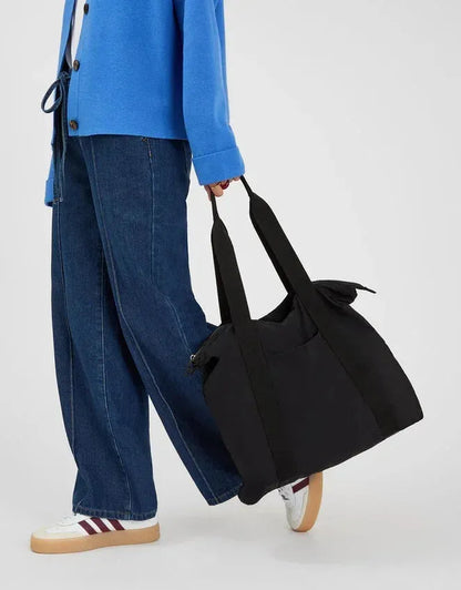 Black travel tote bag with long handles and soft, structured shape